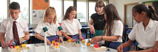 A group of children conducting a physics experiment with their teacher.
